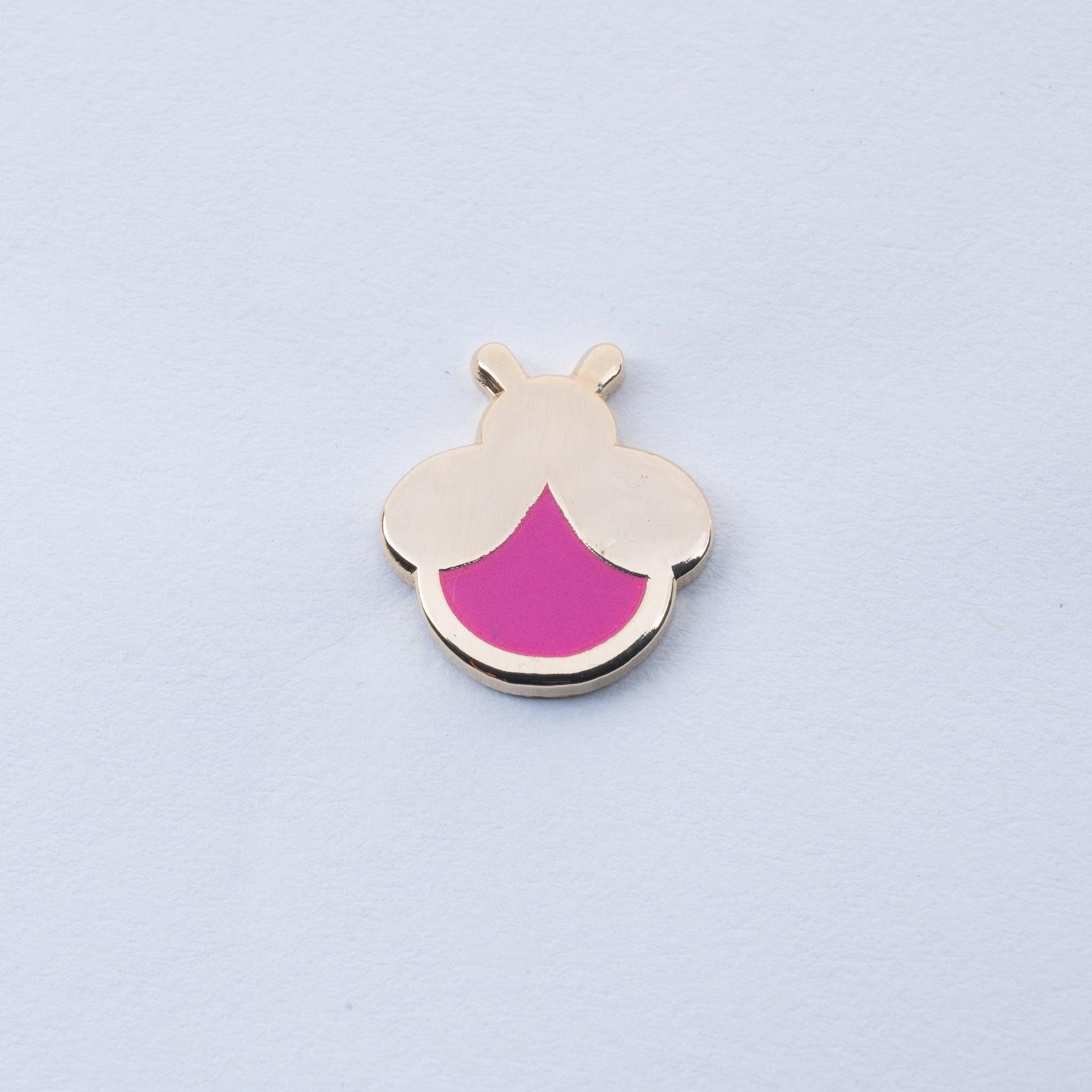 gold plated firefly enamel pin with magenta body that glows in the dark