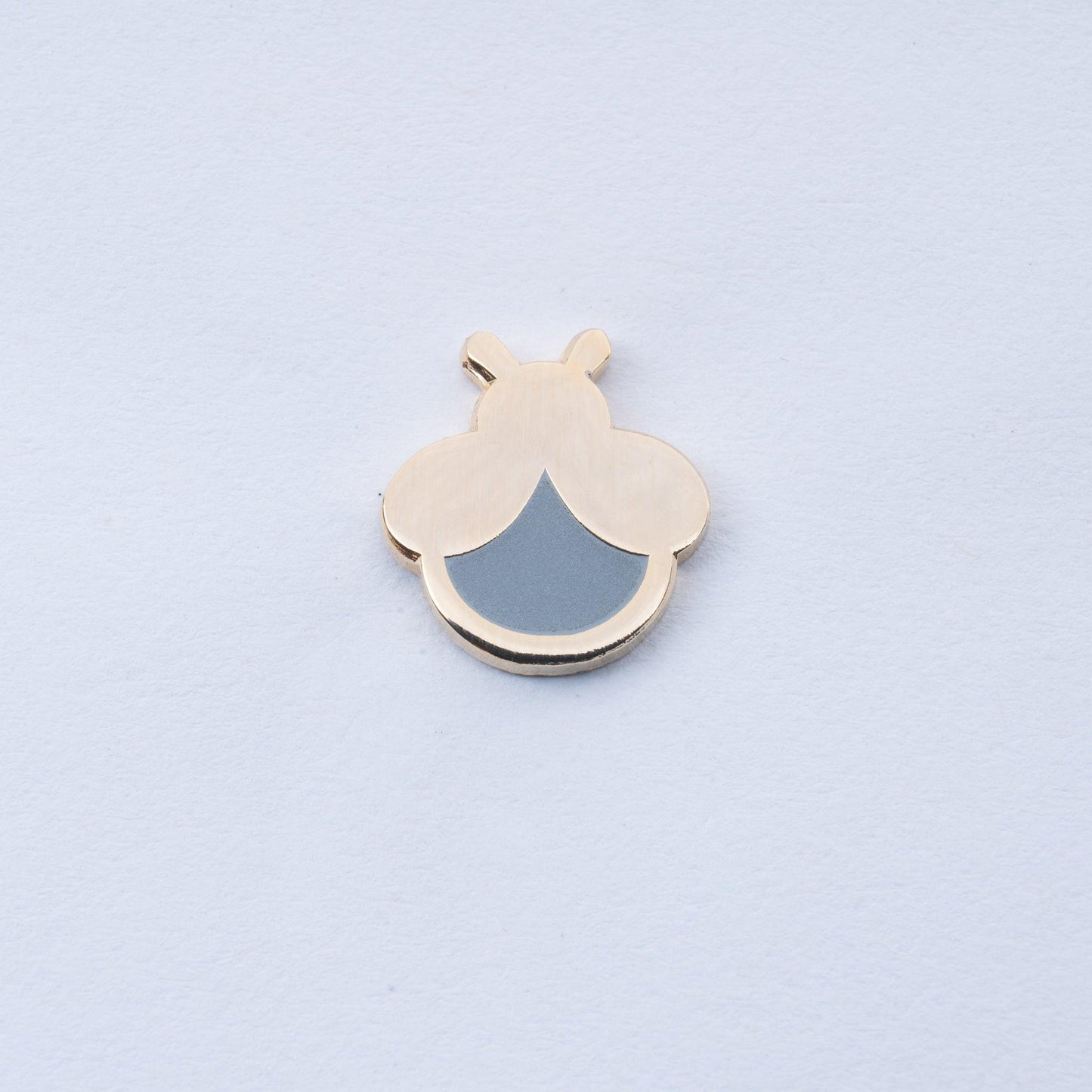 gold plated mini firefly enamel pin with grey body that glows in the dark