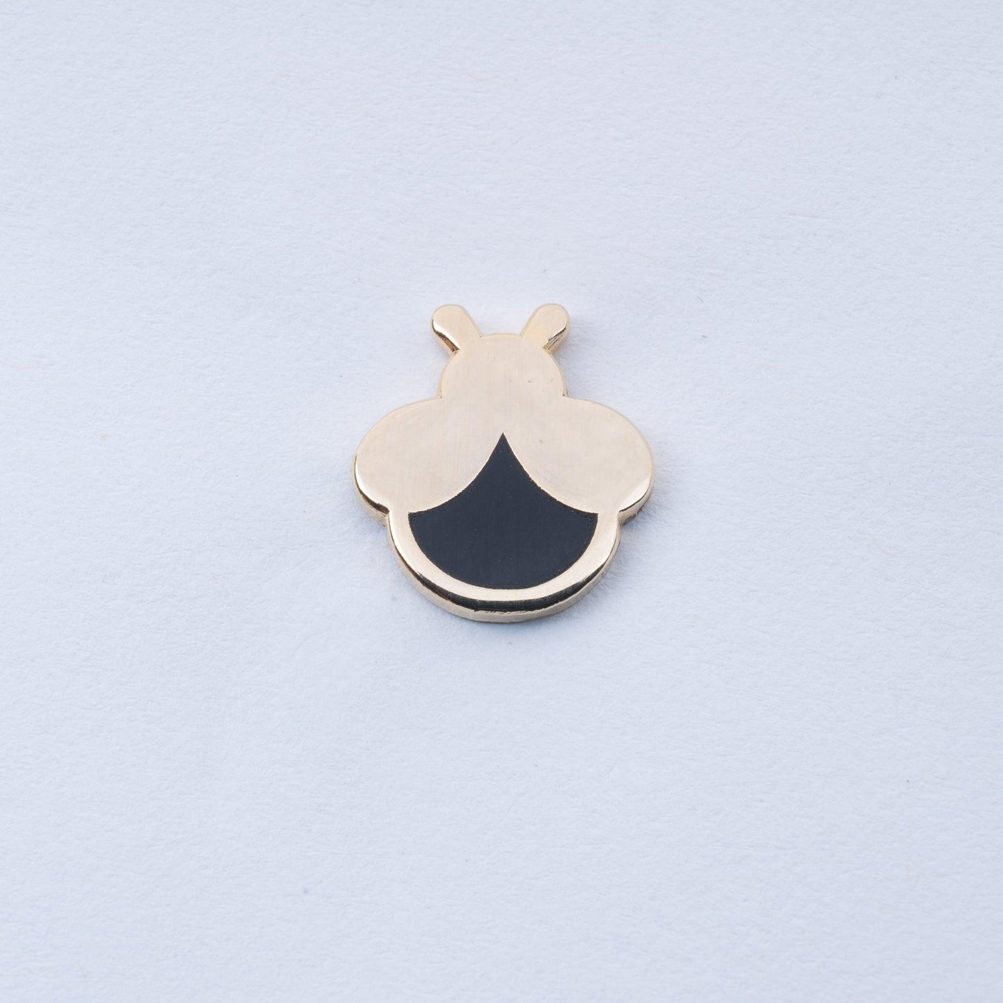 gold plated mini firefly enamel pin with black body that glows in the dark