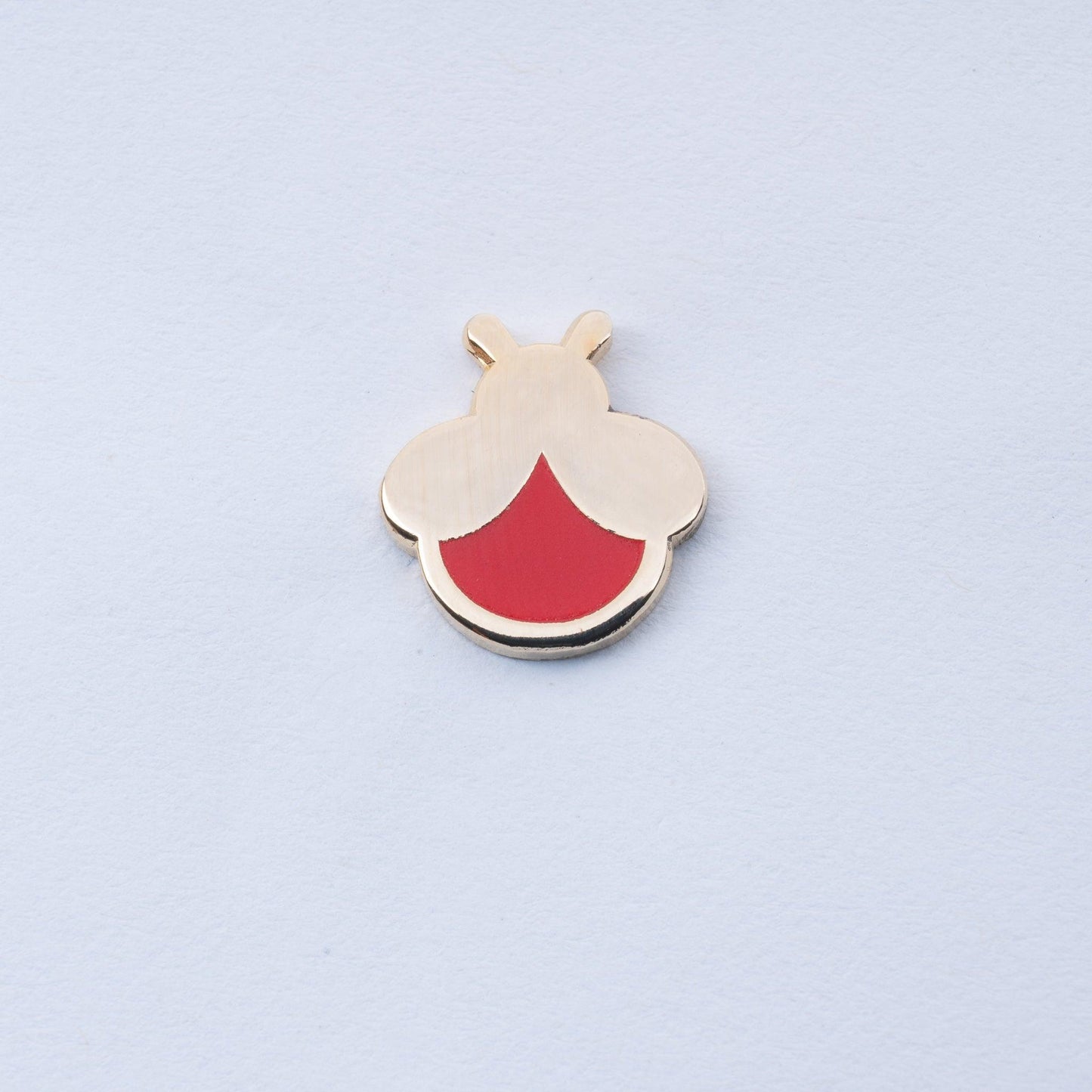 gold plated mini firefly enamel pin with red body that glows in the dark