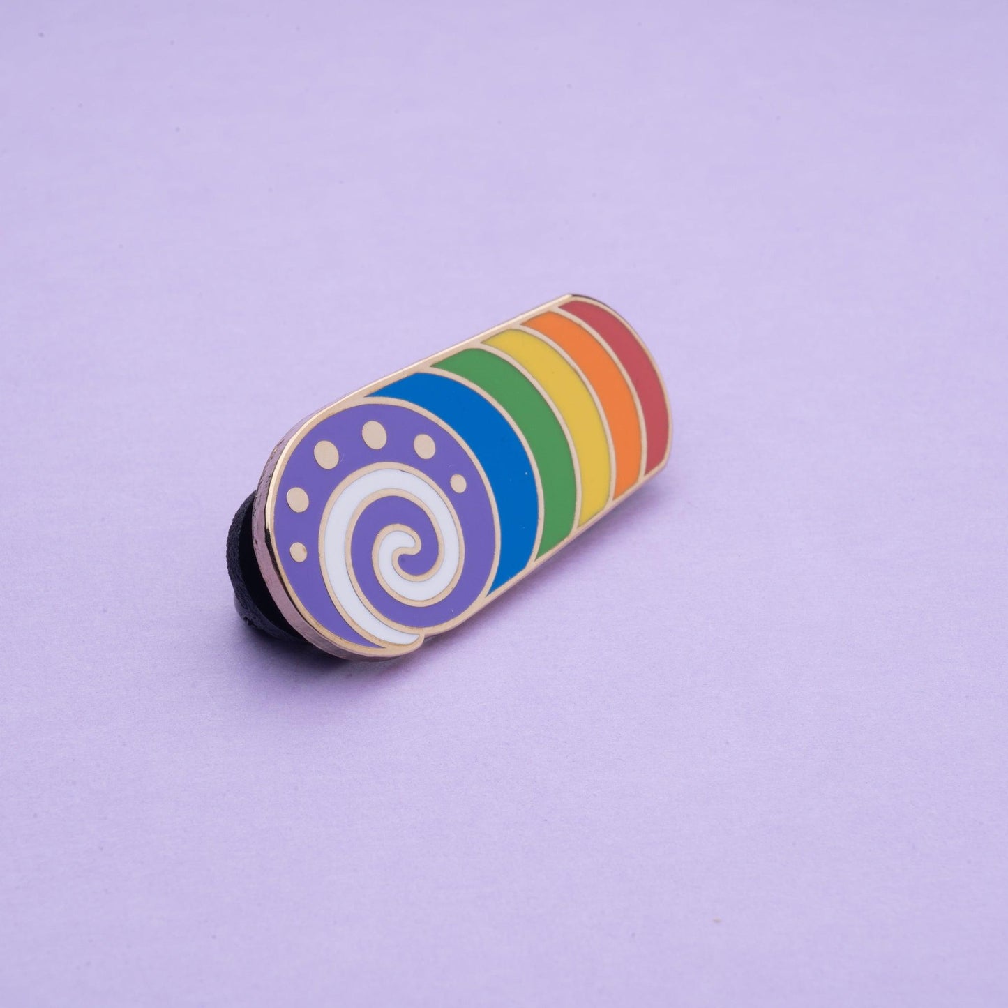 rainbow cake swirl enamel pin where each section is a different colour of the rainbow with purple at the front and a white cream swirl