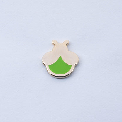 gold plated firefly enamel pin with light green body that glows in the dark