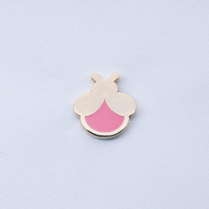 gold plated firefly enamel pin with pink body that glows in the dark