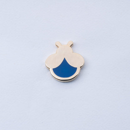 gold plated mini firefly enamel pin with navy blue body that glows in the dark