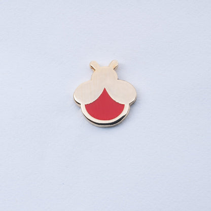 gold plated mini firefly enamel pin with red body that glows in the dark