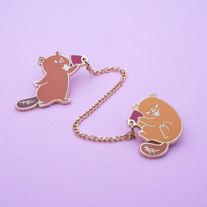 cute beaver pins each holding a red cup to its ear, attached by a chain